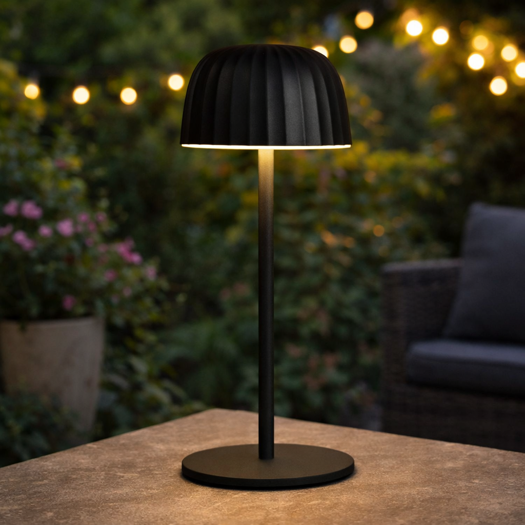 Black outdoor table lamp on a wooden surface with blurred garden background