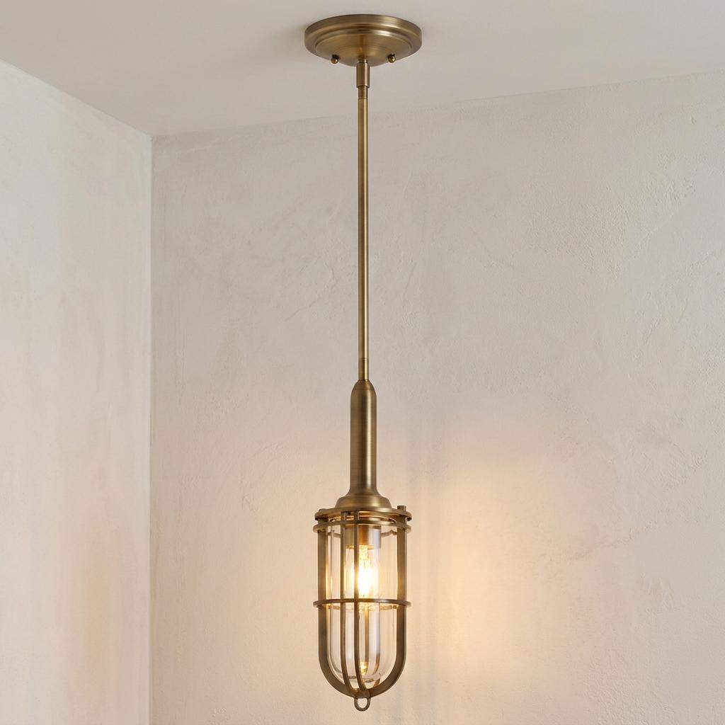 Brass pendant light with a caged glass cylinder shade hanging from a plain white ceiling.