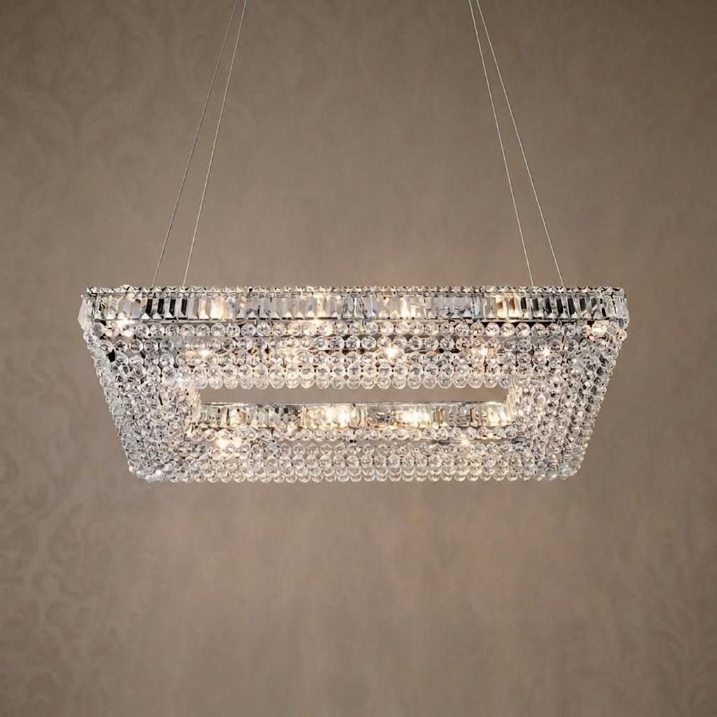 Rectangular chrome ceiling pendant adorned with tiered crystal beads hanging from thin wires against a brown background.