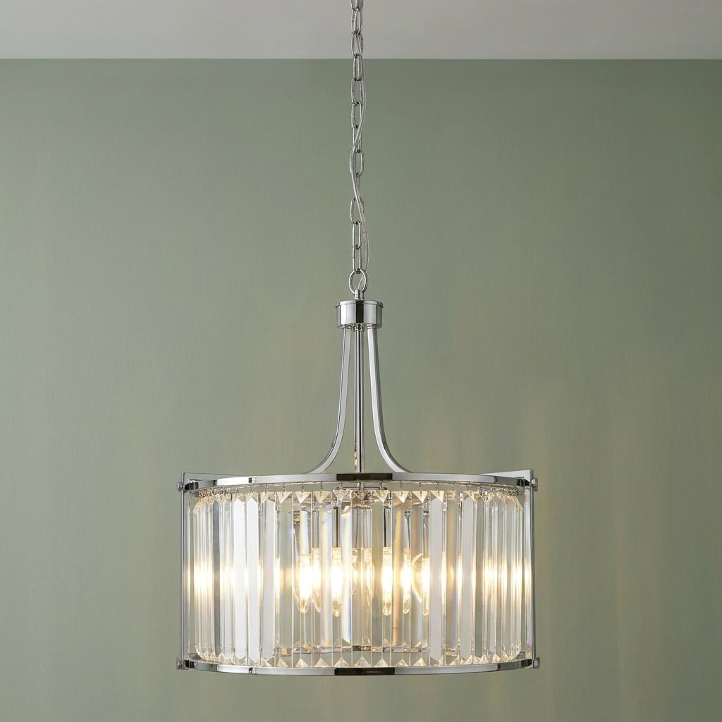Five-light chrome drum pendant with vertical crystal glass rods hanging against a light green wall.