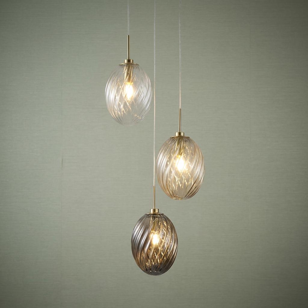 Whirl 3-light multi-drop pendant with satin brass fittings and swirl-patterned glass globes against a green wall.