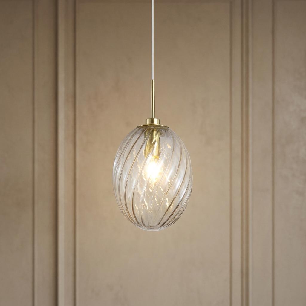 Lit satin brass pendant light with a champagne swirl glass shade against a beige paneled wall.