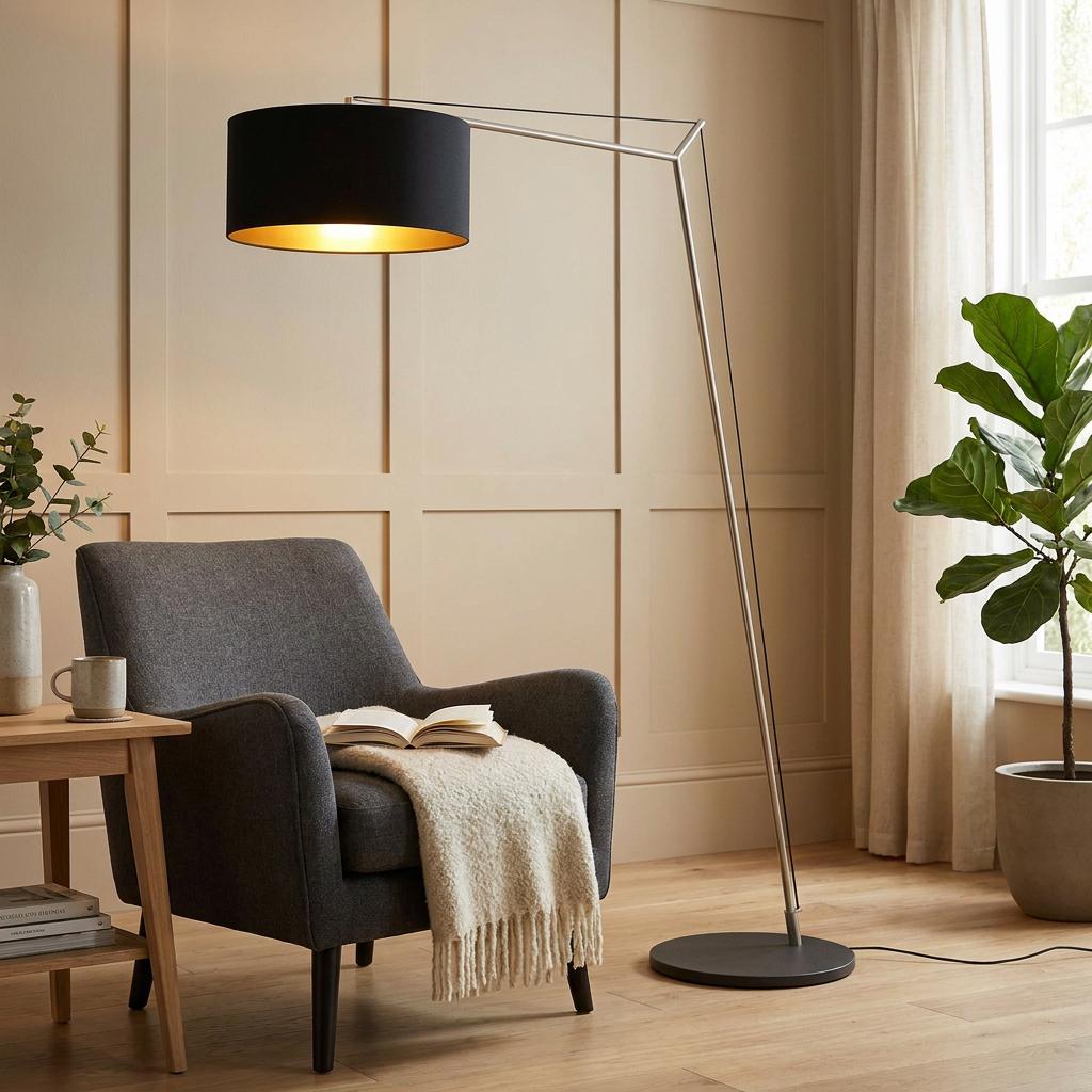 Angular matt nickel floor lamp with a black shade arching over a grey armchair in a modern living room.