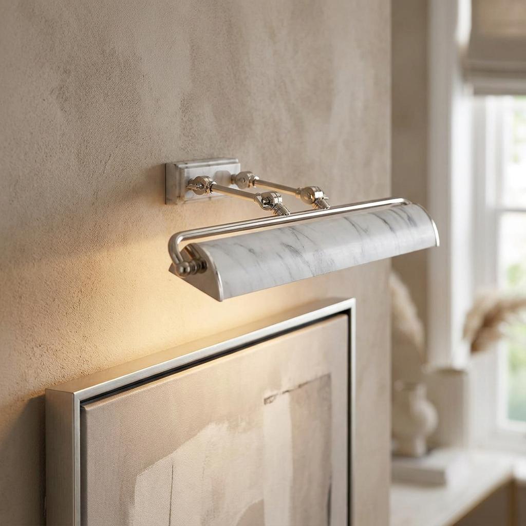 Polished nickel picture light with a white marble shade illuminates a canvas on a textured neutral wall.