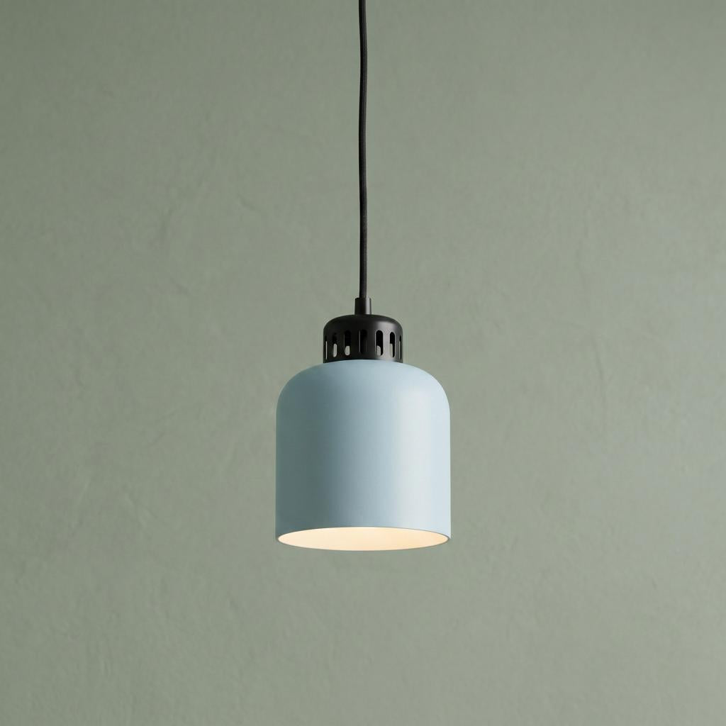 Pale blue canister pendant light with black industrial detailing, illuminated against a sage green wall.