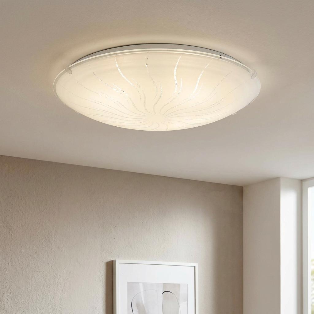 Round white glass LED ceiling light with crystalline swirl pattern mounted on a ceiling above a grey wall.