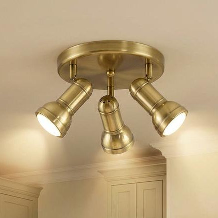 A modern semi-flush mount ceiling light fixture with four adjustable brushed brass/gold spotlight heads, installed in a kitchen ceiling above a marble island.