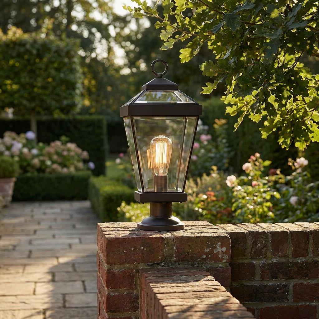 Traditional bronze pedestal lantern with a glowing Edison bulb mounted on a brick garden wall.